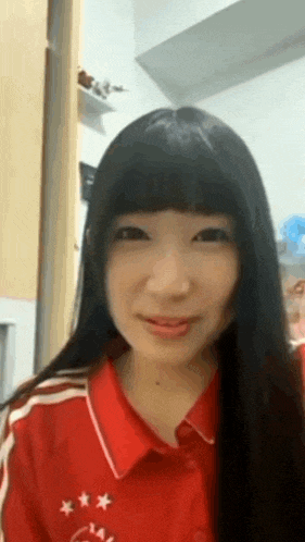 a woman with long black hair is wearing a red shirt with stars on it and smiling .