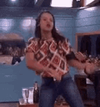 a woman is dancing in a room with a blue wall behind her .