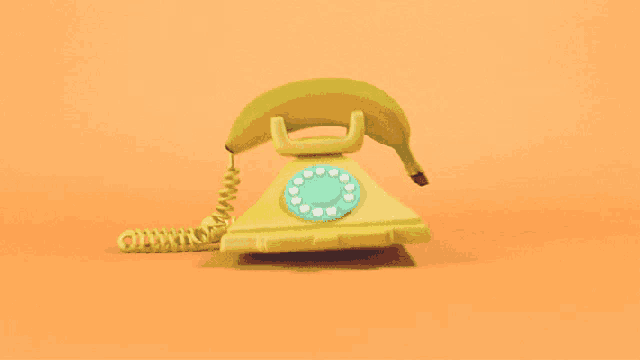 a yellow telephone with a banana on the top of it