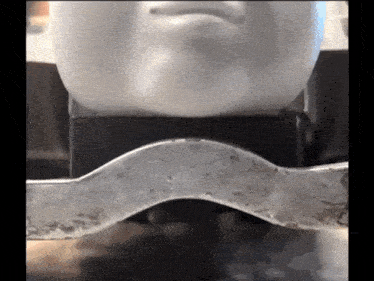 a statue of a man 's face is sitting on a metal bar
