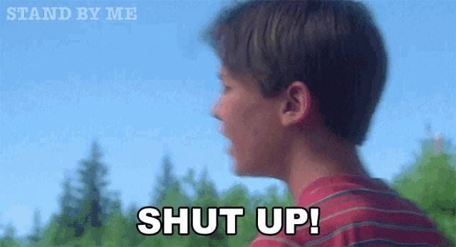 a man in a red shirt says shut up in front of trees