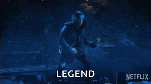 a man is playing a guitar on a stage in front of a crowd and the word legend is on the screen .