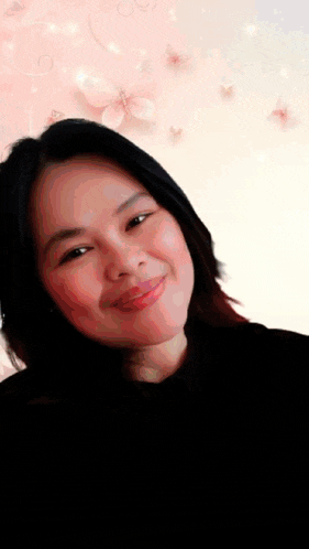a woman is smiling in front of a pink background