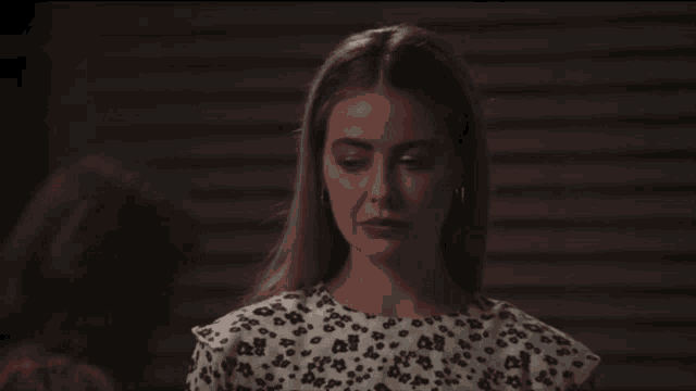 a woman in a leopard print top looks down