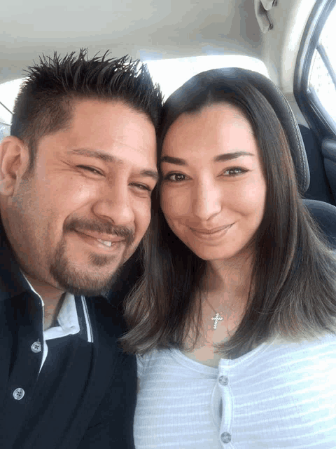 a man and a woman are posing for a picture in the back seat of a car