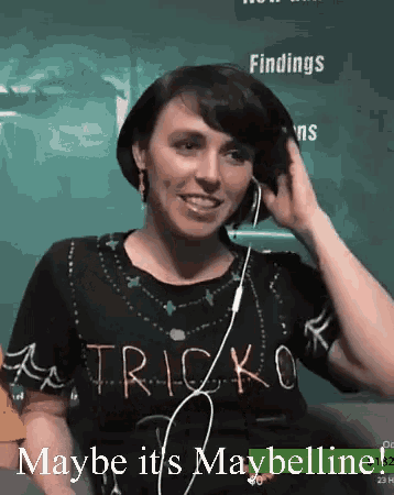 a woman wearing headphones and a tricko shirt says maybe it 's maybelline on the bottom
