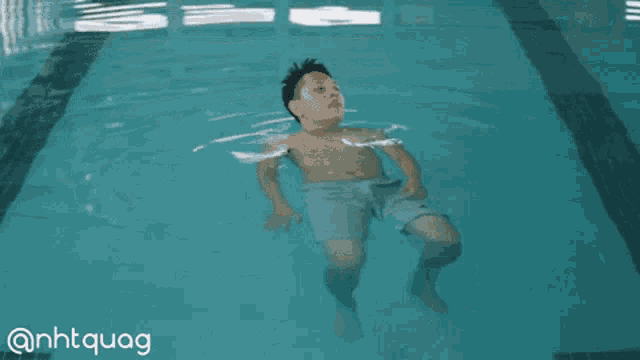 a boy is floating in a swimming pool with the hashtag @nhtquag