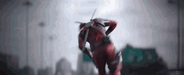 a man in a superhero costume is running with a sword in his hand .