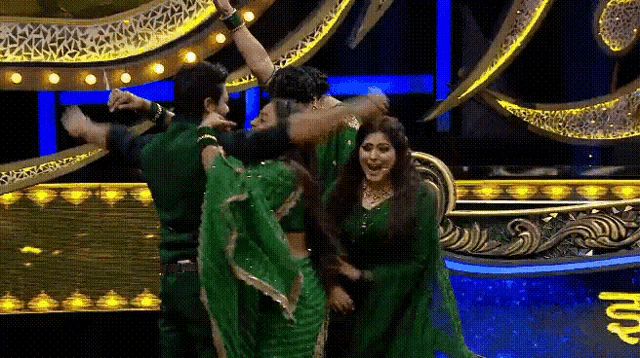 a group of people in green dresses are dancing on a stage .