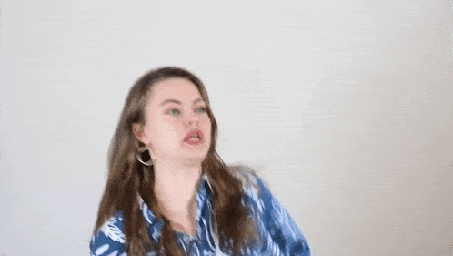 a woman in a blue shirt is blowing her hair in the wind .