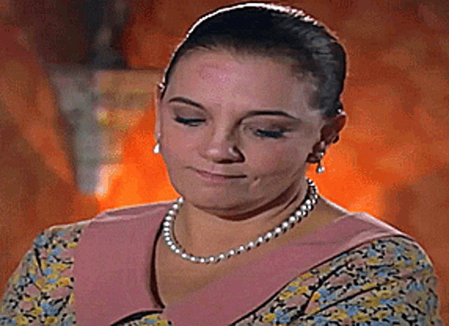 a woman with a kiss on her forehead wearing a pearl necklace