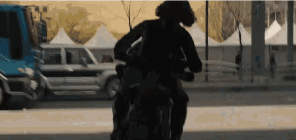 a person is riding a motorcycle down a street in the city .