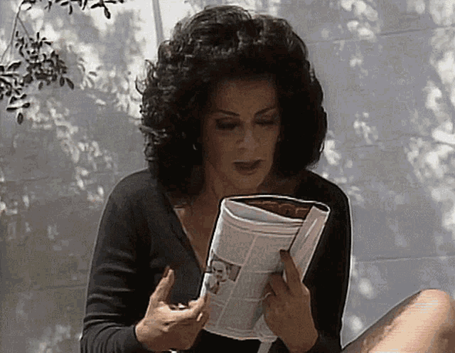 a woman is reading a magazine with a picture of a man on the cover
