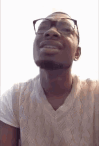 a man wearing glasses and a sweater is smiling .
