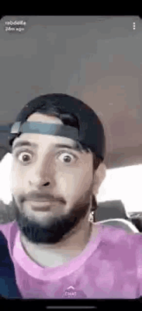 a man with a beard and a hat is making a funny face while sitting in a car .