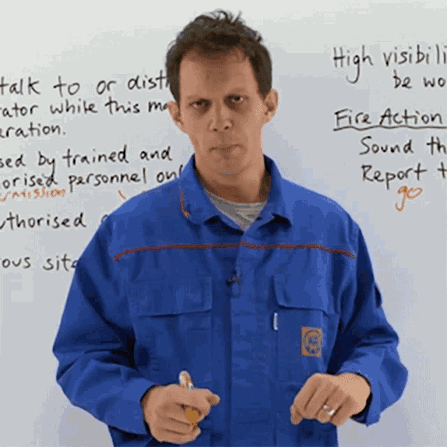 a man in a blue jacket stands in front of a white board that says high visibility be worn