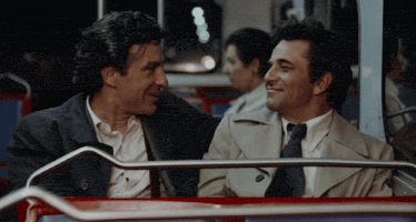 two men are sitting on a bus and looking at each other