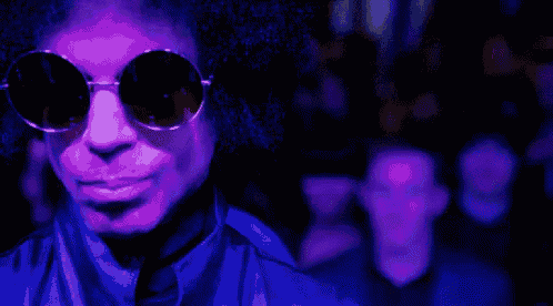 a man wearing sunglasses and a purple jacket