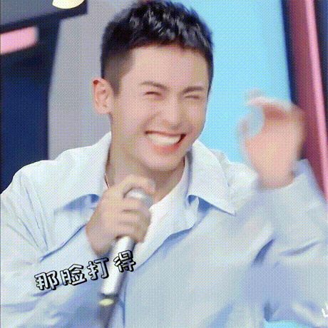 a man in a blue shirt is holding a microphone and laughing .