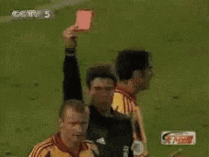 a referee holds up a red card in front of a player wearing a yellow jersey with the number 22 on it