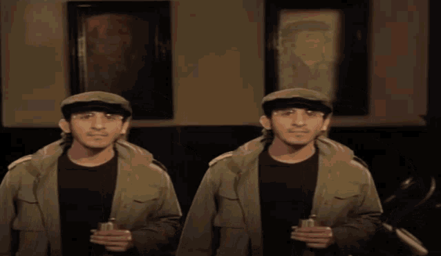 two men in green jackets and hats are standing next to each other holding drinks