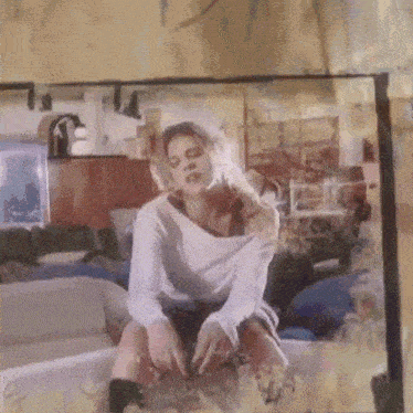 a woman in a white shirt is sitting on a couch in a room