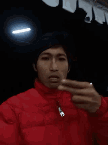 a man wearing a red jacket is giving a peace sign