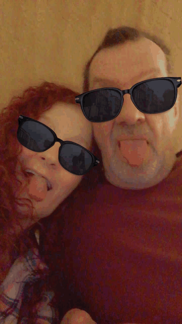 a man and a woman wearing sunglasses stick their tongues out