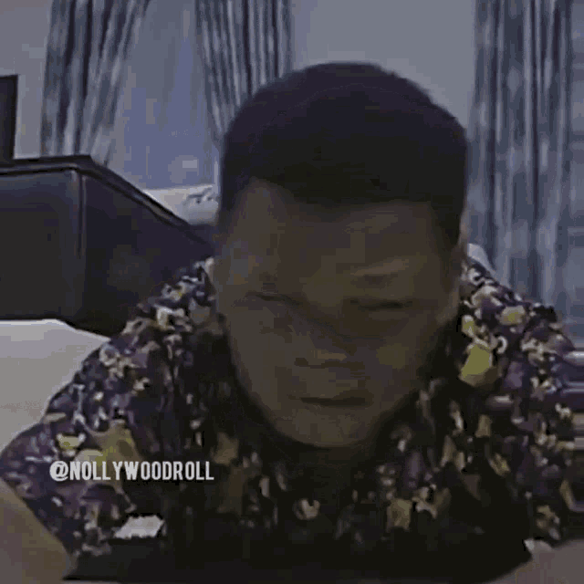 a man in a purple shirt is laying on a table with his hands on the table