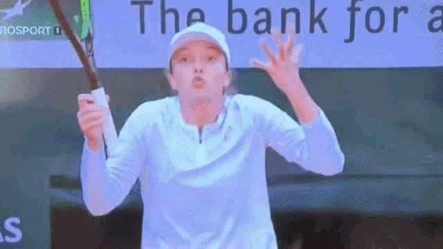 a woman is holding a tennis racquet in front of a sign that says the bank for a ..
