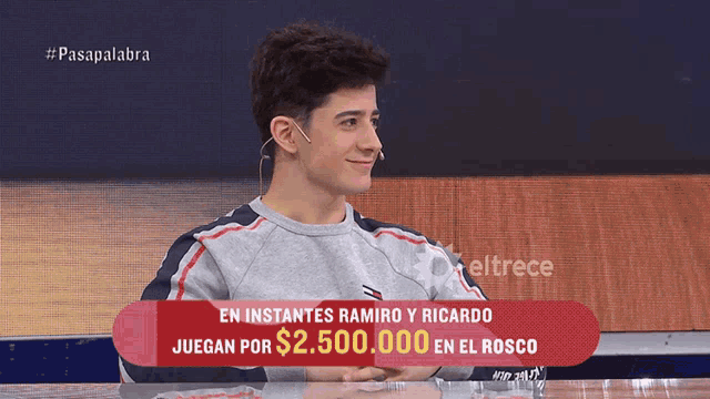 a young man sitting at a table with a red sign that says en instantes ramiro y ricardo