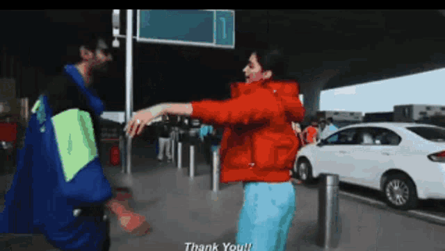 a woman in a red jacket is hugging a man in a blue jacket with the words thank you on the bottom