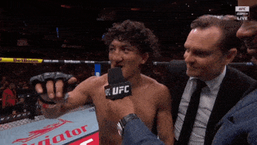 a man in a suit is talking into a microphone with ufc on it