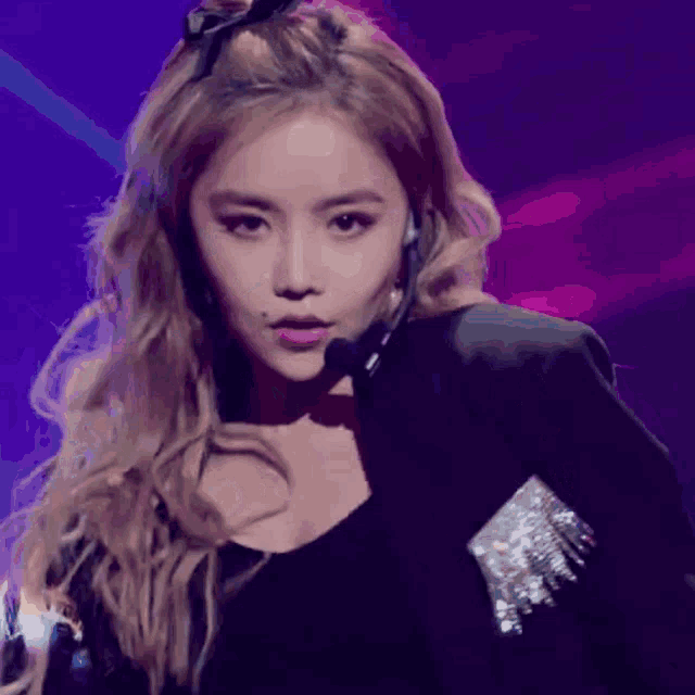 a woman with blonde hair is wearing a black jacket and earrings