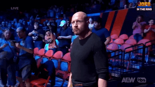 a bald man is standing in front of a crowd in a wrestling ring .
