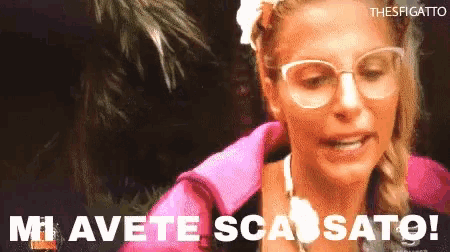 a woman wearing glasses and a pink jacket says mi avete scassato