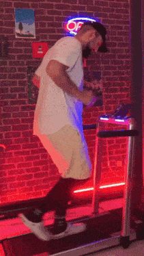a man is standing on a treadmill in a room with a brick wall .