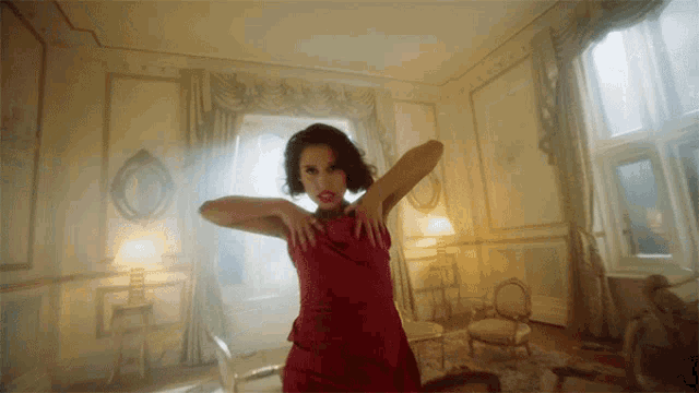 a woman in a red dress dancing in a living room