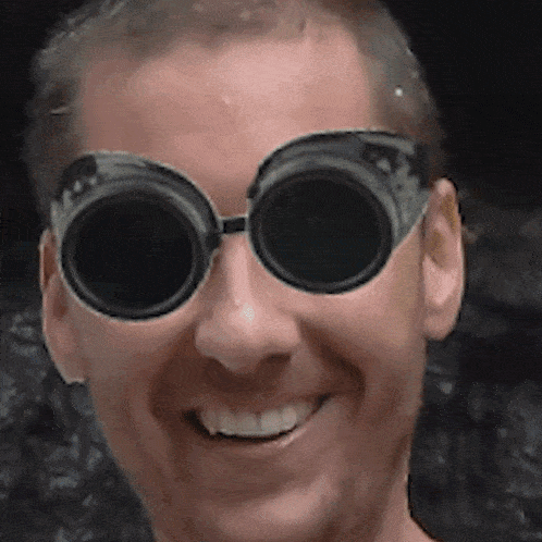 a man wearing a pair of goggles is smiling for the camera
