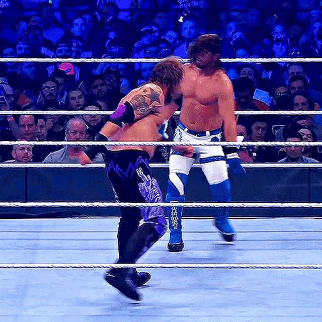 two men are wrestling in a ring and one has a tattoo on his back