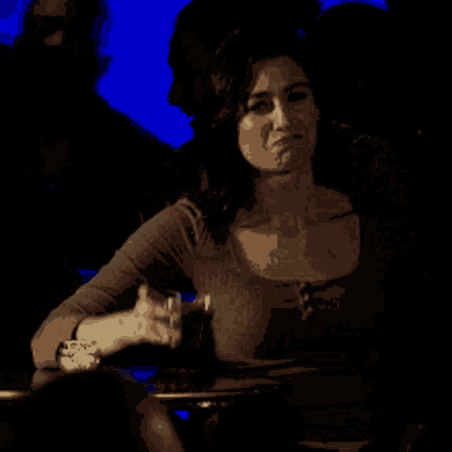 a woman is sitting at a table with a glass of wine in her hand