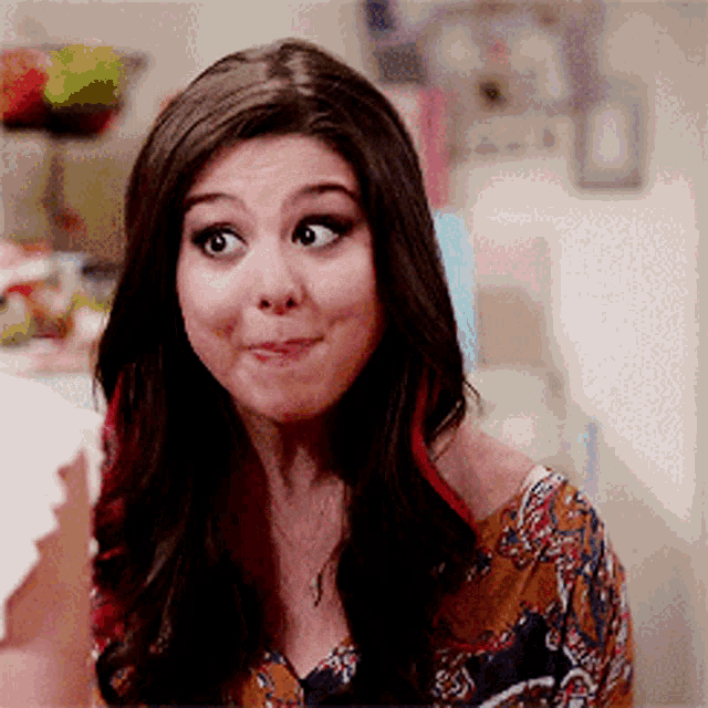 a woman is making a funny face while wearing a floral shirt