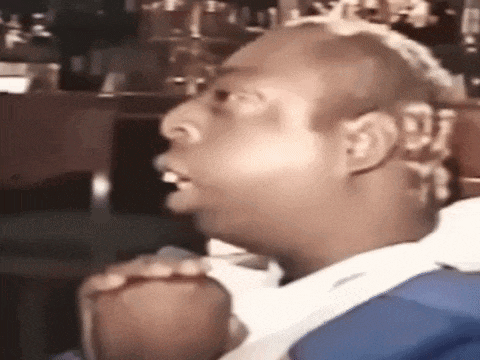 a man with a shaved head is sitting in a chair with his mouth open and looking at the camera .