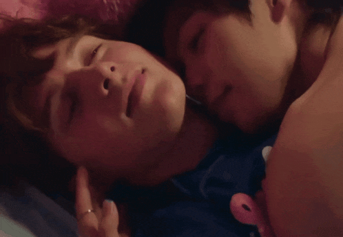 a man and a woman are laying on a bed and the woman is wearing a ring on her finger