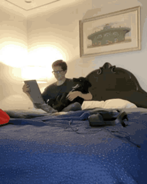 a man is sitting on a bed with a dog and a laptop