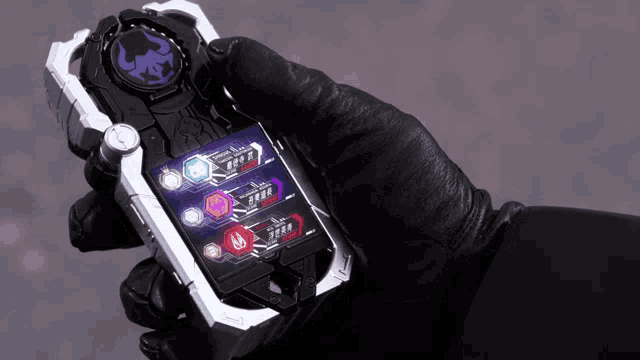 a person in a black glove is holding a cell phone with three buttons on it