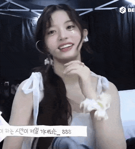 a girl in a white dress is smiling with korean writing on the bottom right