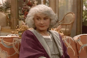 an elderly woman is sitting on a couch wearing a purple robe .