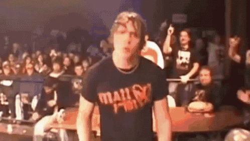 a man is standing in front of a crowd wearing a t-shirt that says ' heavy metal ' .