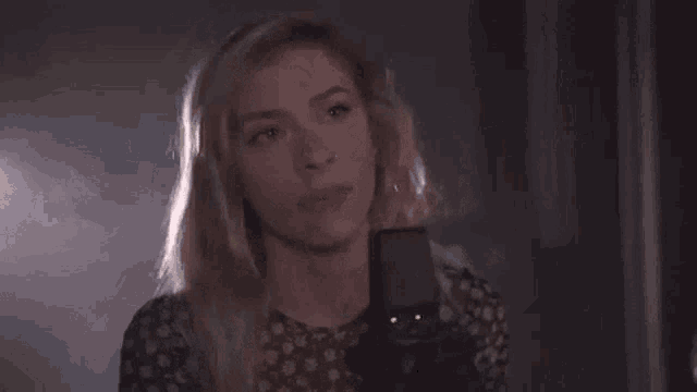 a woman is singing into a microphone in a dark room in a dark room .